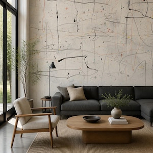 May include: A living room featuring a large charcoal gray sectional sofa, a light beige armchair with wooden arms, and an oval wooden coffee table. The wall behind the sofa displays a large-scale mural with abstract black lines and colorful dots.