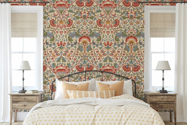 Puede incluir: Un dormitorio con una cama que presenta una cabecera con estampado y un papel tapiz floral con acentos rojos, azules y verdes. La cama tiene un edred&oacute;n blanco y almohadas con estampado amarillo.