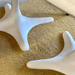 Pode incluir: Duas bases de mesa brancas com um design de tr&ecirc;s pontas. As bases est&atilde;o sobre um tapete bege.