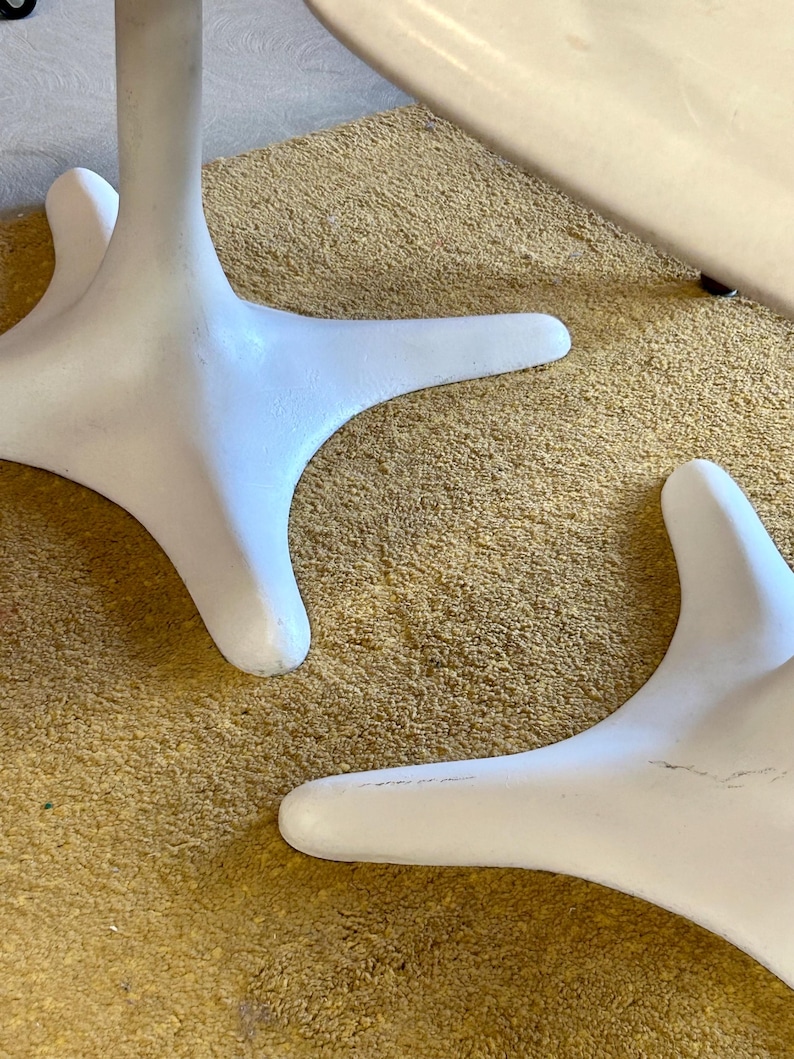 Pode incluir: Duas bases de mesa brancas com um design de tr&ecirc;s pontas. As bases est&atilde;o sobre um tapete bege.