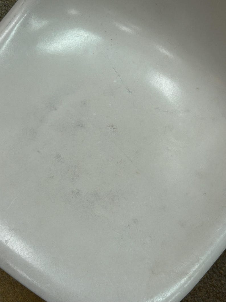 Pode incluir: Assento de cadeira de pl&aacute;stico branco com alguns arranh&otilde;es e marcas leves.