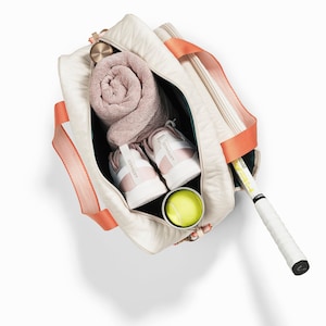 Tennis bag in quilted white vegan leather with orange webbing and solid golden metal pullers.