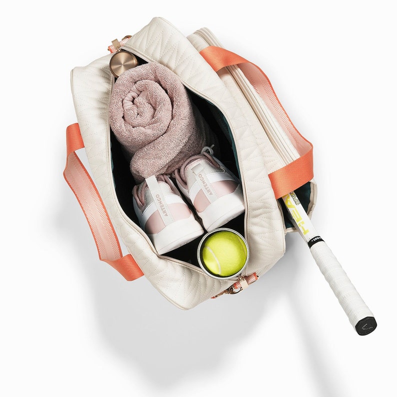 Tennis bag in quilted white vegan leather with orange webbing and solid golden metal pullers.