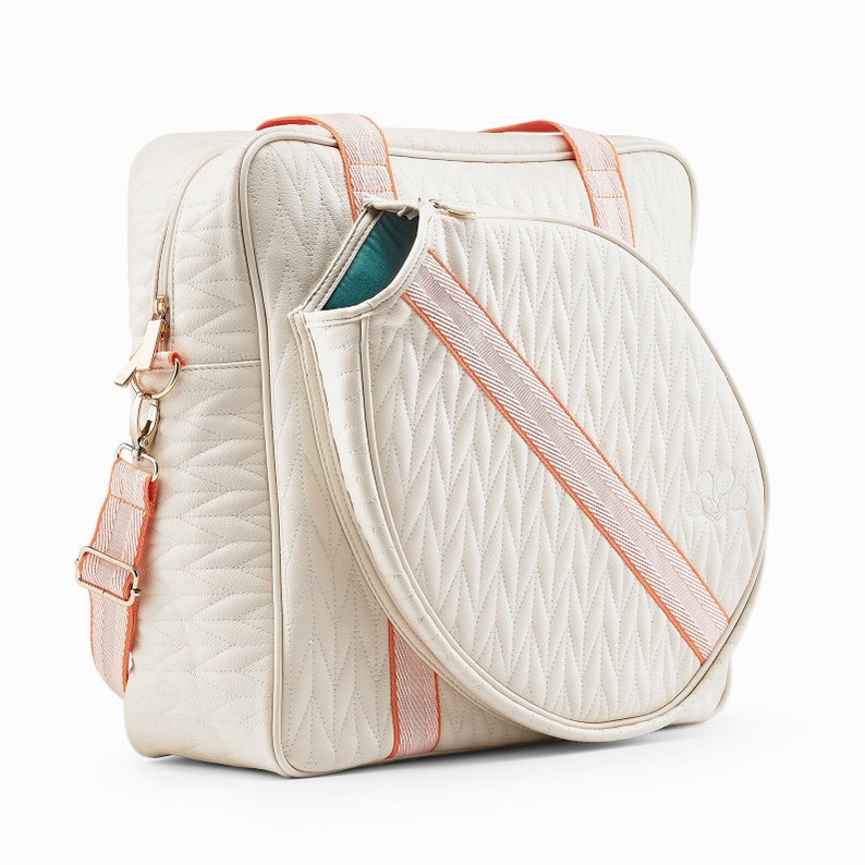 Tennis bag in exclusive quilted white vegan leather with orange webbing and solid golden metal pullers. The tennis bag has green inner lining.