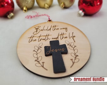 May include: A round wooden Christmas ornament with a black cross and the words "Behold the way the truth and the life Jesus" engraved on it.