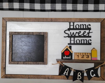 May include: A wooden framed sign with a chalkboard insert, a small shelf with a schoolhouse, ruler, pencil, and a banner with the letters A, B, and C. The sign says "Home Sweet Home".