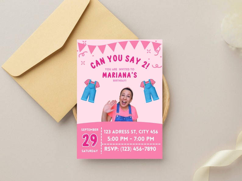 May include: A pink birthday invitation with the text "Can You Say 2!" and "Mariana's Birthday!" features illustrations of overalls. The invitation includes the date, time, and RSVP information. An envelope is in the background.