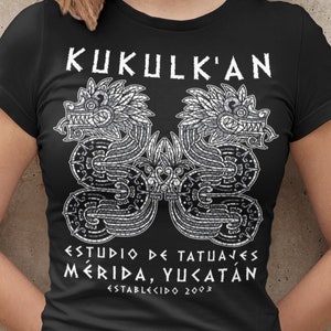 May include: Black t-shirt with a white graphic of two mythical creatures with the text "KUKULK'AN ESTUDIO DE TATUAJES MERIDA, YUCATAN ESTABLECIDO 2003"