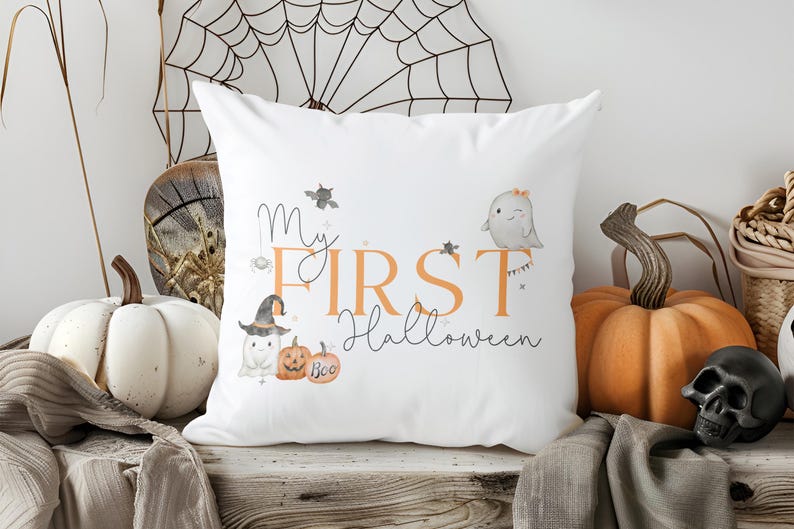 May include: A white square throw pillow featuring a printed graphic with the text My FIRST Halloween in orange and black script. The design includes illustrations of two small ghosts, a pumpkin with the word Boo, a bat, and a spider.