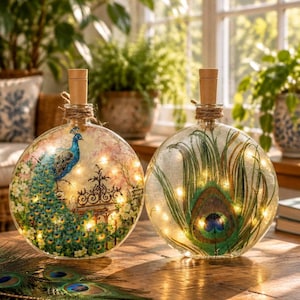 May include: Two round glass bottles with cork stoppers, illuminated by internal string lights. One bottle features a peacock perched on a gate, while the other displays a large peacock feather. Both are wrapped with twine at the neck.