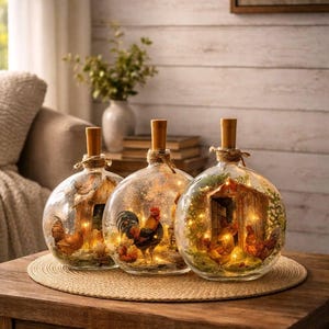 May include: Three glass bottles with wooden stoppers, each showcasing a farm scene with chickens and a rooster, lit by fairy lights. The bottles sit on a wooden table with a woven mat.