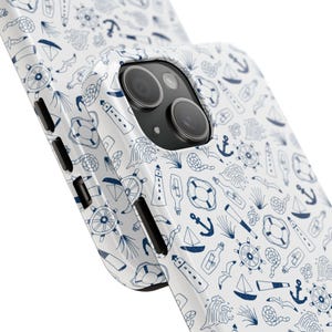 Puede incluir: Funda de tel&eacute;fono blanca con un dise&ntilde;o n&aacute;utico. El patr&oacute;n presenta ilustraciones azules de anclas, veleros, salvavidas y faros. La funda es brillante y envuelve el tel&eacute;fono, mostrando la c&aacute;mara y los botones laterales.