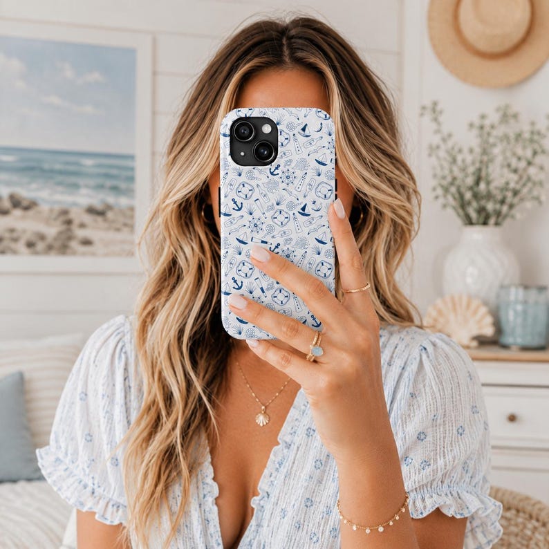 Puede incluir: Funda de tel&eacute;fono blanca con un dise&ntilde;o n&aacute;utico azul que incluye anclas, veleros y br&uacute;julas. La funda tiene un acabado brillante y un recorte para la c&aacute;mara. La funda del tel&eacute;fono se sostiene frente a la cara de una persona.
