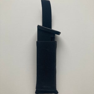 May include: A black nylon magazine pouch with a velcro closure and a black magazine inside.