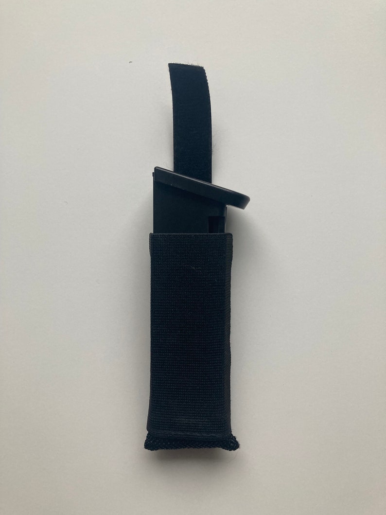 May include: A black nylon magazine pouch with a velcro closure and a black magazine inside.