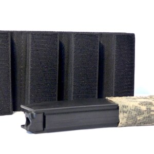 May include: A black magazine pouch with three rows of hook and loop fasteners. A black magazine with a camouflage wrap is shown next to the pouch.