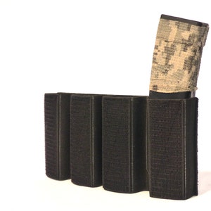 May include: A black tactical magazine pouch with four slots for holding magazines. A camouflage-patterned magazine is inserted into one of the slots.