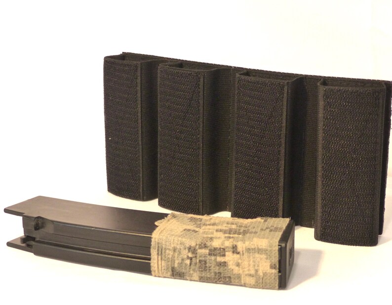 May include: A black tactical magazine pouch with four slots for magazines. The pouch has a hook and loop closure and is made of durable nylon. A black magazine with a camouflage wrap is in front of the pouch.
