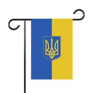 May include: A blue and yellow garden flag with the Ukrainian coat of arms, a gold trident, in the center.