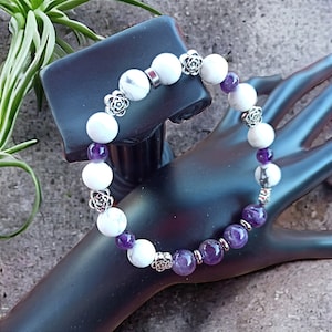 Può includere: Un braccialetto realizzato con perline bianche di howlite, perline di ametista e accenti floreali argentati.