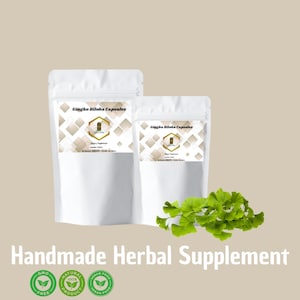 May include: Two white pouches of Gingko Biloba Capsules with a green sprig of leaves. The pouches have labels with text and a geometric design. The words "Handmade Herbal Supplement" are at the bottom, along with three green circular logos.