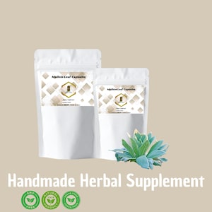 May include: Two white pouches of Mullein Leaf Capsules, a dietary supplement, are displayed. The image includes a sprig of green and blue-green leaves and the text "Handmade Herbal Supplement" with accompanying logos for GMO-free, natural product, and vegan food.