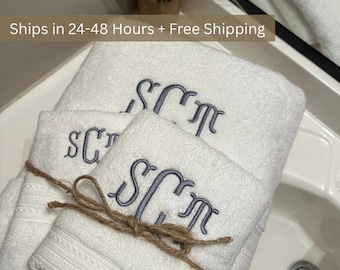 May include: White monogrammed towel set with embroidered initials in a stylish script. The towels are tied together with twine and are displayed near a sink. The text "Ships in 24-48 Hours + Free Shipping" is visible in the image.