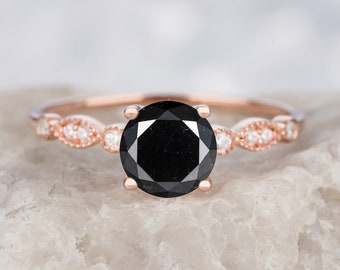May include: A rose gold engagement ring with a black diamond center stone and a band accented with small white diamonds.