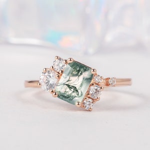 Puede incluir: Un anillo de oro rosa con una piedra preciosa de ágata verde musgo rodeada de pequeñas piedras preciosas transparentes.
