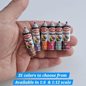 May include: Miniature Krylon ColorMaster spray paint cans in various colors, held in a hand. The cans are labeled with the Krylon logo and product details. Text at the bottom reads "31 colors to choose from" and "Available in 1:6 & 1:12 scale."