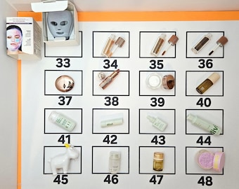 May include: A collection of beauty and skincare products arranged in a numbered grid from 33 to 48. Items include lip glosses, lipsticks, creams, serums, a face mask, and a small white goat figurine, all displayed on a white background.
