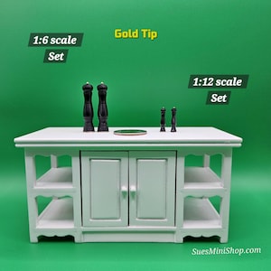 May include: Miniature kitchen island with black salt and pepper shakers. The island is white with two doors and shelves. The text "Gold Tip", "1:6 scale Set", and "1:12 scale Set" are visible.
