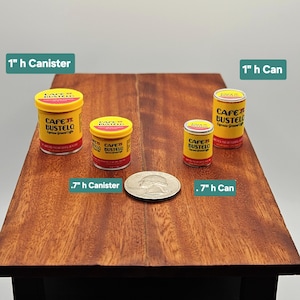 May include: Four miniature Cafe Bustelo coffee containers in yellow and red. Two canisters measure 1 inch and 0.7 inches in height, and two cans measure 1 inch and 0.7 inches in height. A US quarter coin is placed in the center for scale.