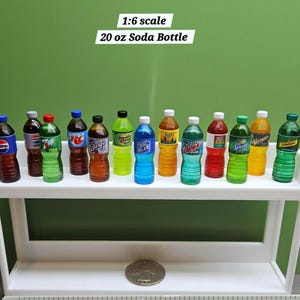 Puede incluir: Botellas de refresco en miniatura de varias marcas y colores, incluyendo Pepsi y Sprite, exhibidas en una estanter&iacute;a blanca. Las botellas est&aacute;n etiquetadas como "20 oz" y son a escala 1:6. El fondo es verde liso.