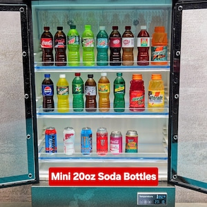 Puede incluir: Un mini-refrigerador lleno de varias botellas y latas de refrescos de 591 ml. El surtido incluye Coca-Cola, Pepsi, Gatorade y otras marcas populares. El refrigerador tiene una pantalla de temperatura digital y el texto "Mini 20oz Soda Bottles".
