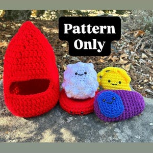 Può includere: Una collezione di oggetti all'uncinetto che include una grande struttura cava rossa, una sfera bianca testurizzata con un volto, una forma arrotondata gialla con un volto e un ovale viola e blu con un volto. Testo Pattern Only.
