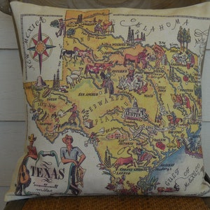 May include: A decorative pillow featuring a vintage-style map of Texas with illustrations of landmarks and animals. The map is surrounded by a beige border and the text "Texas" is written in a stylized font at the bottom.