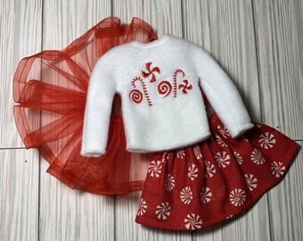 May include: A white sweater with a candy cane and swirl design, a red tulle skirt, and a red skirt with a white candy cane print.