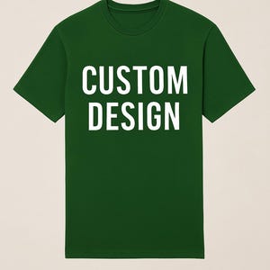 May include: A dark green t-shirt with the words "CUSTOM DESIGN" printed in large, white capital letters. The shirt has a crew neck and short sleeves. The image is a studio shot of the shirt.