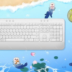 May include: A white wireless keyboard with a numeric keypad sits on a blue and white background with cartoon sea otters and a glass of lemonade. The background is reminiscent of a beach scene.