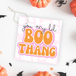 May include: A pink and orange Halloween gift tag with the text "you my lil BOO THANG" on a background of white ghosts.