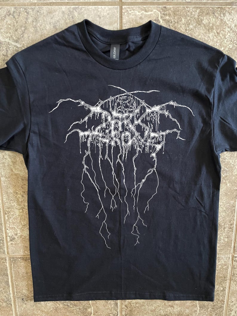 Puede incluir: Camiseta negra con un dise&ntilde;o gr&aacute;fico blanco. El dise&ntilde;o presenta texto estilizado y un pentagrama. La camiseta est&aacute; hecha de un material suave y tiene cuello redondo.