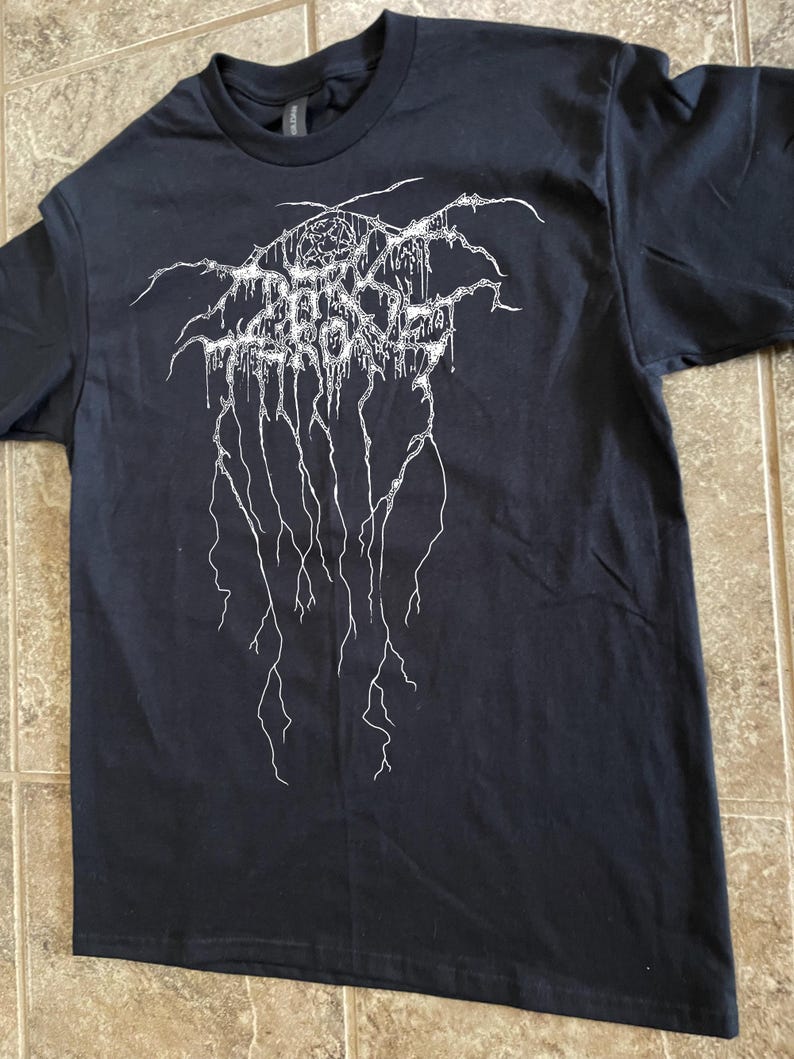 Puede incluir: Camiseta negra con un dise&ntilde;o gr&aacute;fico blanco. El dise&ntilde;o presenta texto estilizado y l&iacute;neas goteantes. La camiseta est&aacute; hecha de un material suave y tiene cuello redondo.