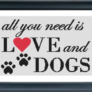 May include: Framed artwork with the text "all you need is LOVE and DOGS." The word "LOVE" features a red heart, and black paw prints are below. The text is in black on a white background, framed in a dark blue frame.