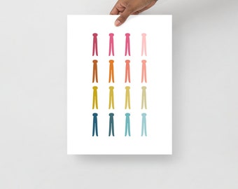 Op de afbeelding: Een digitale print met een regenboogkleurige gradiënt van 20 gestileerde wasknijpers in een verticale rij.