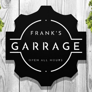 May include: Black and white sign with a gear shape and the text "Frank's Garage Open All Hours".
