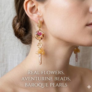 Peut inclure: Boucles d'oreilles dorées avec un motif floral, des perles d'aventurine et des perles baroques. Les boucles d'oreilles présentent un élément circulaire avec des fleurs séchées encapsulées dans de la résine, un connecteur en forme de fleur et une perle pendante.