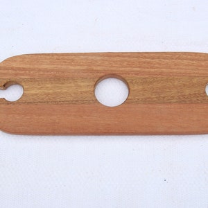 May include: A wooden serving tray with two cutouts for holding wine glasses and a centre hole for a bottle. The tray is made of light brown wood with a natural grain pattern.