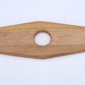 May include: Wooden wine bottle holder with two cutouts for bottles and a larger centre cutout for a bottle neck. The holder is made of light brown wood.