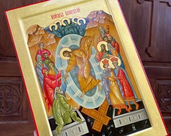 May include: A hand-painted icon depicting the Resurrection of Jesus Christ. The icon features a gold background with a red border. The central figure of Jesus is depicted in a white robe, ascending from a tomb. The tomb is surrounded by a group of figures, including angels and soldiers. The icon is inscribed with the text "Иисуса воскресли" in Cyrillic.